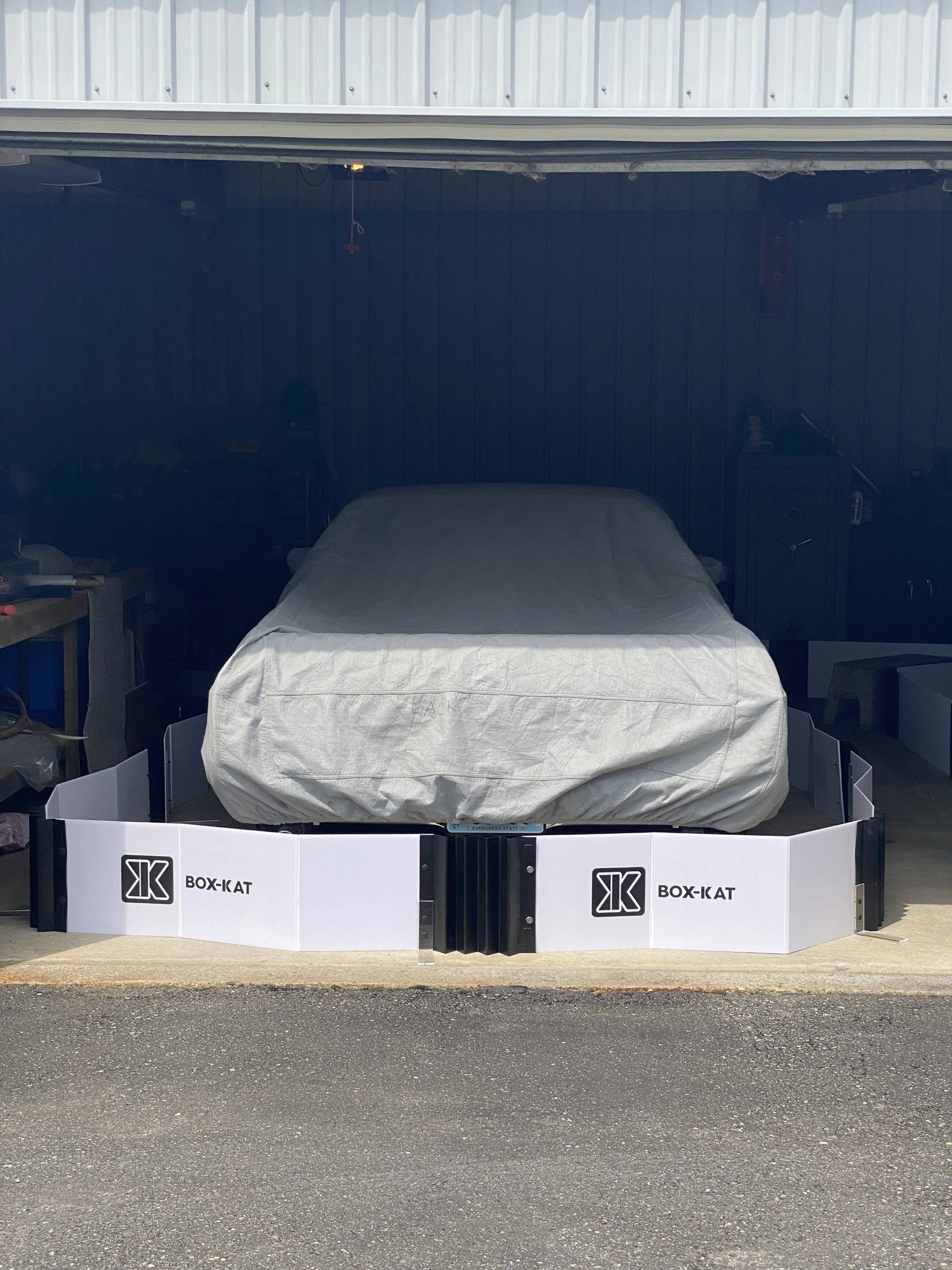 Car covered with a white tarp in garage with Box-Kat mouse barrier surrounding it
