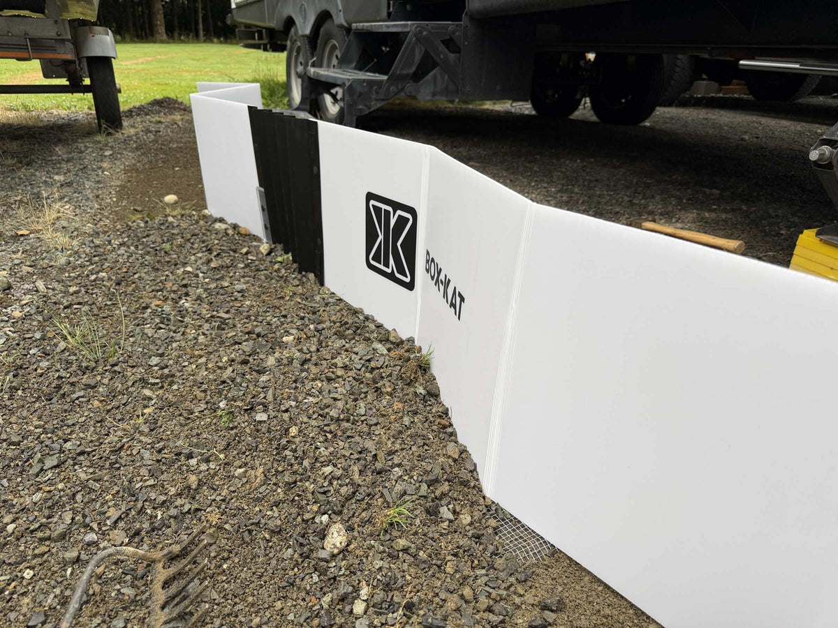Box-Kat mouse barrier set up on gravel beside a travel trailer