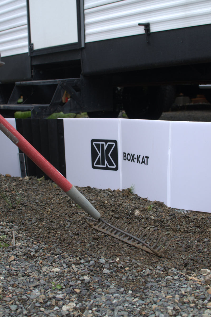 Raking gravel level beside a white Box-Kat panel before setup